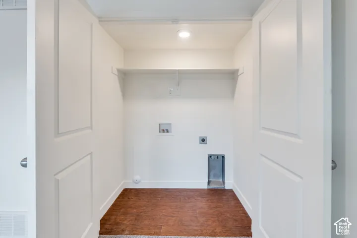 Laundry alcove featuring a recessed light, built-in shelving, utility hookups, and wood-finish flooring