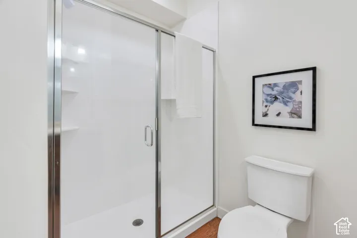 White shower enclosure with clear glass sliding door and integrated shelving