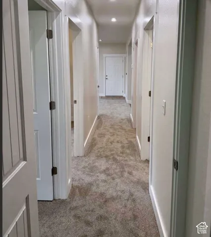 Recessed lighting illuminates the carpeted hallway with multiple panel doors