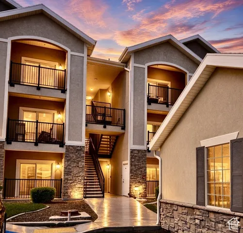 Stucco exterior with stone accents, multiple private balconies, exterior staircase, and exterior lighting