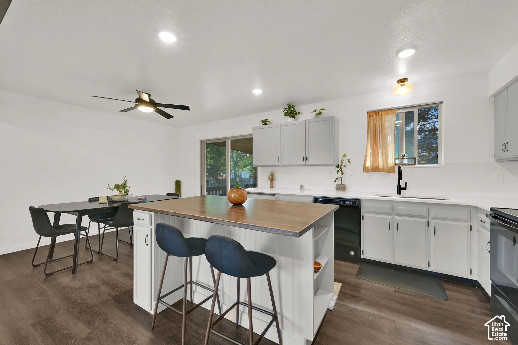 Kitchen featuring white cabinetry, wood-finish flooring, a center island with a wood-finish countertop, and a sliding glass door