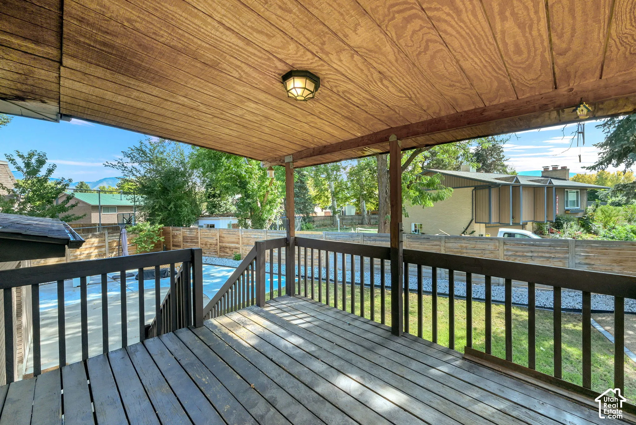 Covered deck off kitchen featuring wood-finish ceiling, mounted light fixture, and wood deck flooring