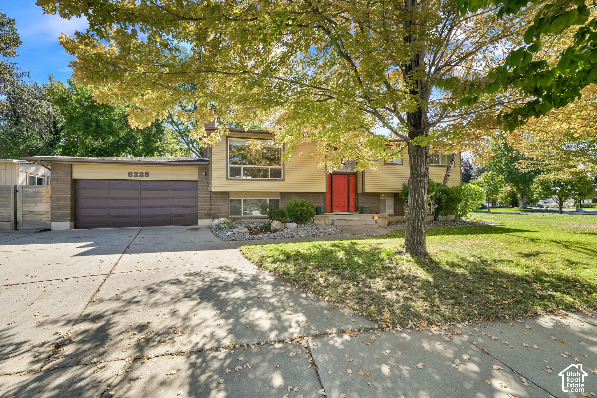 Split-level exterior featuring a red front door, large windows, and an integrated garage