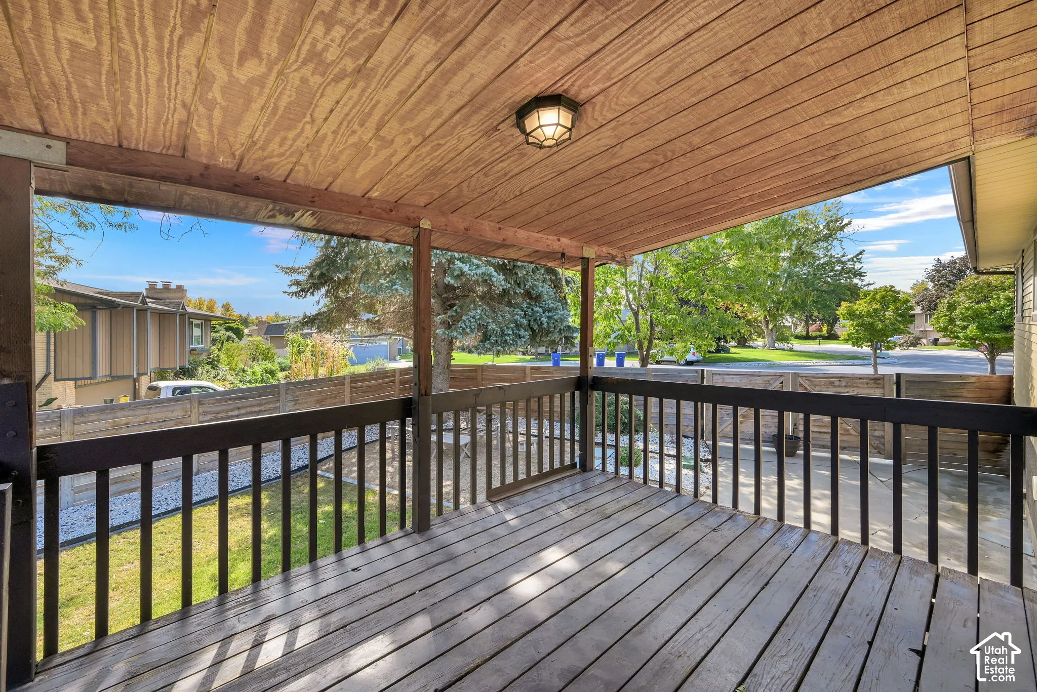 Covered deck off kitchen with wood-finish flooring, wood ceiling, and a dark-toned railing