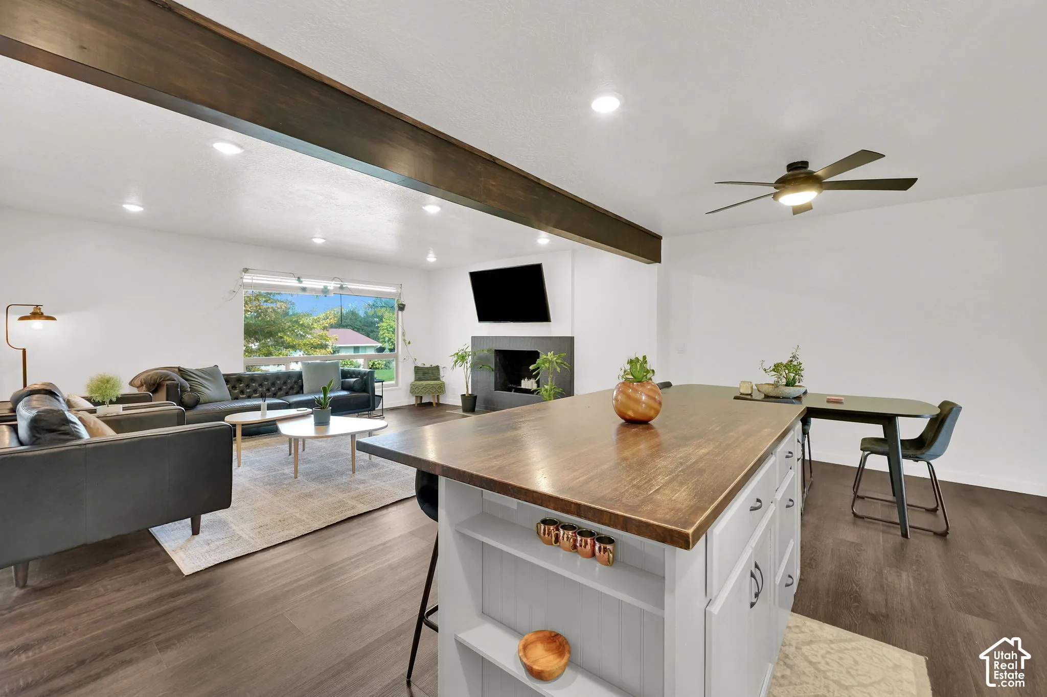 Recessed lighting, wood-finish flooring, exposed ceiling beam, kitchen island with built-in storage, and ceiling fan