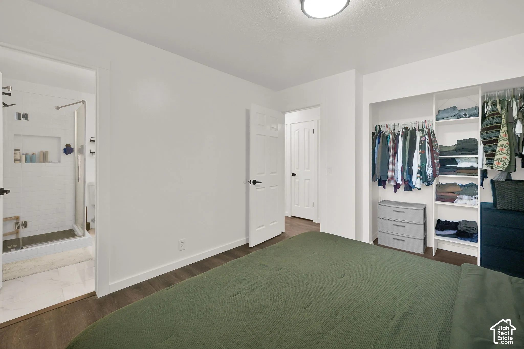 Main 3rd Bedroom with private bath. White walls with wood-finish flooring, built-in closet organization, and a flush-mount ceiling light