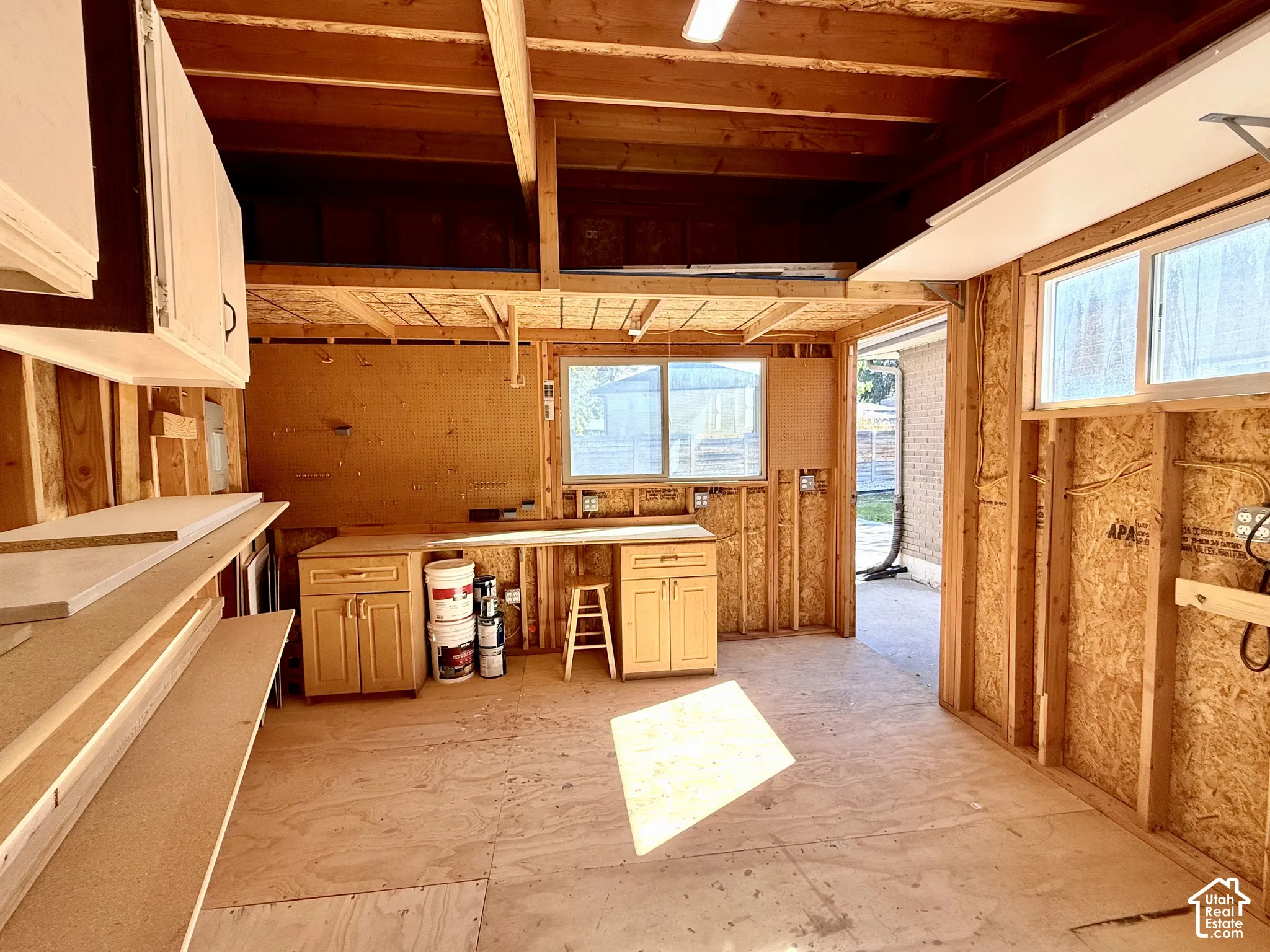 Exposed wood framing with built-in cabinetry, overhead storage, multiple windows, and power.