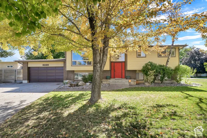 Split-level residence featuring a prominent red entry door, horizontal siding, and a two-car garage