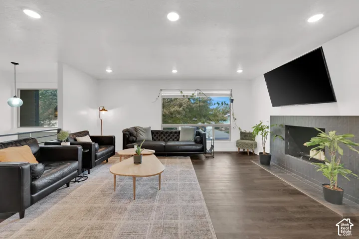 Recessed lighting, wood-finish flooring, large window, fireplace with dark tile surround, and an open-concept layout