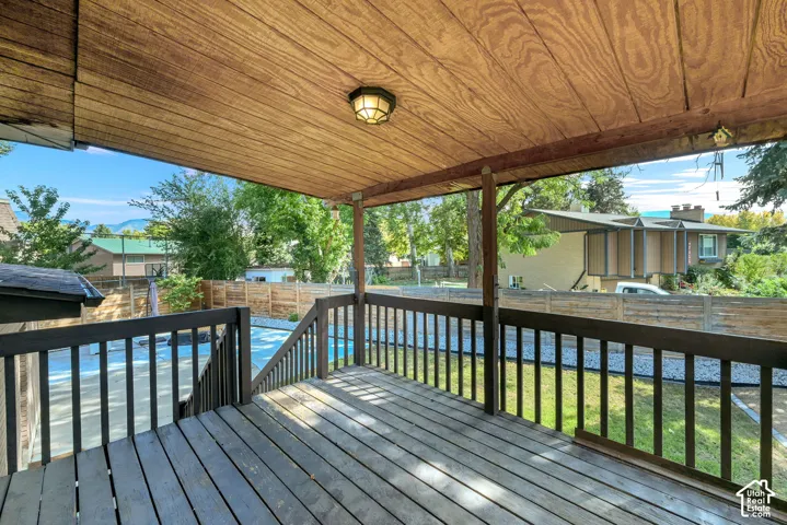 Covered deck off kitchen featuring wood-finish ceiling, mounted light fixture, and wood deck flooring