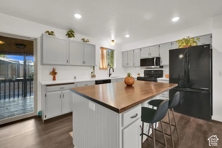 Kitchen featuring a wood-finish island countertop, gray cabinetry, white countertops, and dark wood-finish flooring