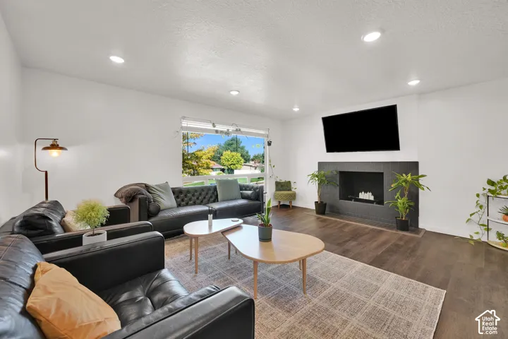 Spacious living area featuring recessed lighting, large window with outdoor scenery, modern fireplace with a dark tile surround, and wood-finish flooring