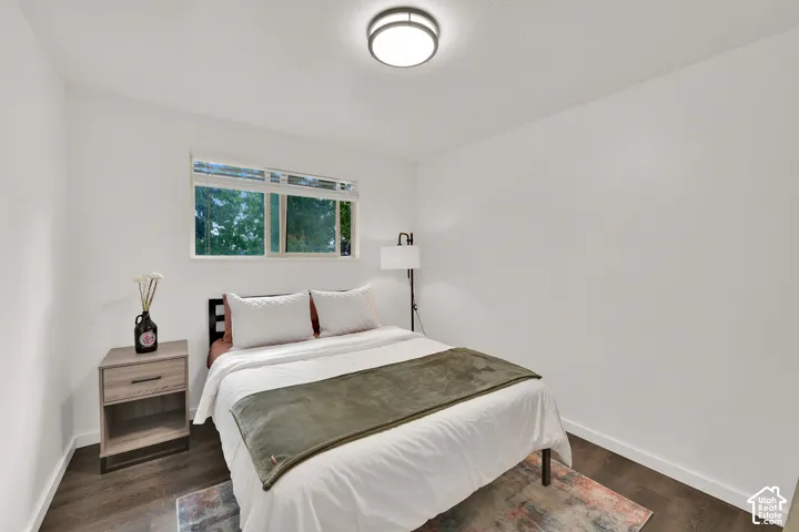 2nd Main Floor Bedroom. Recessed window featuring white blinds, dark wood-finish flooring, and a flush mount ceiling light fixture