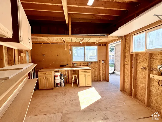 Exposed wood framing with built-in cabinetry, overhead storage, multiple windows, and power.