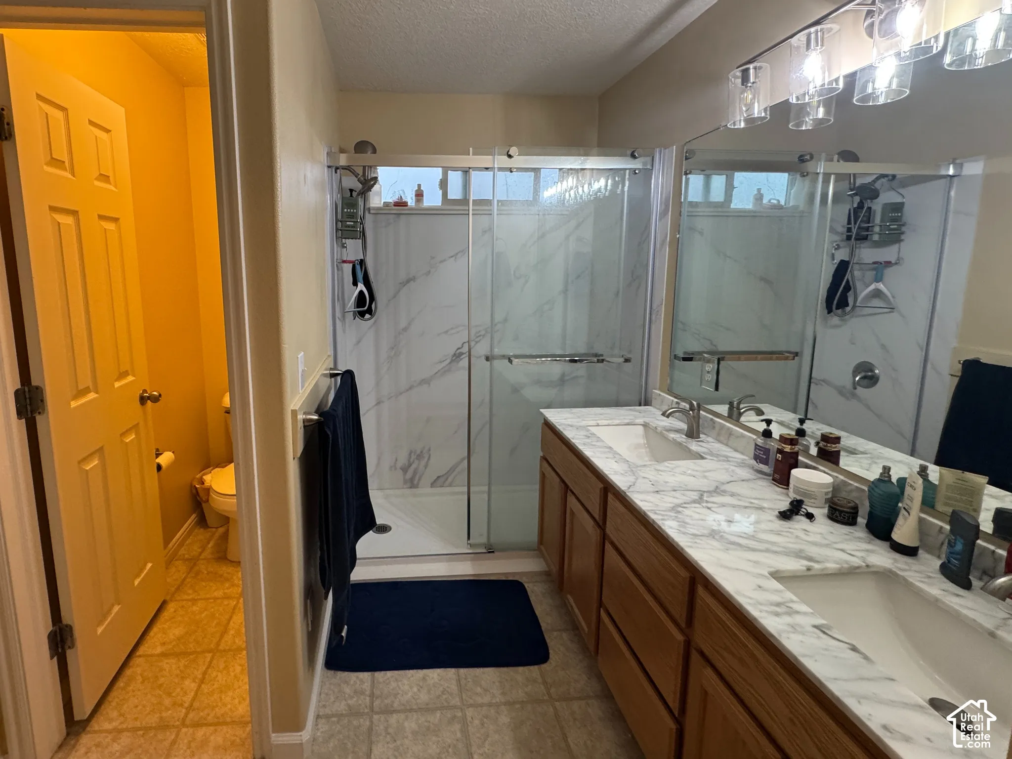 Primary Bathroom Dual vanity with integrated sinks, full-width mirror, and overhead linear light fixture