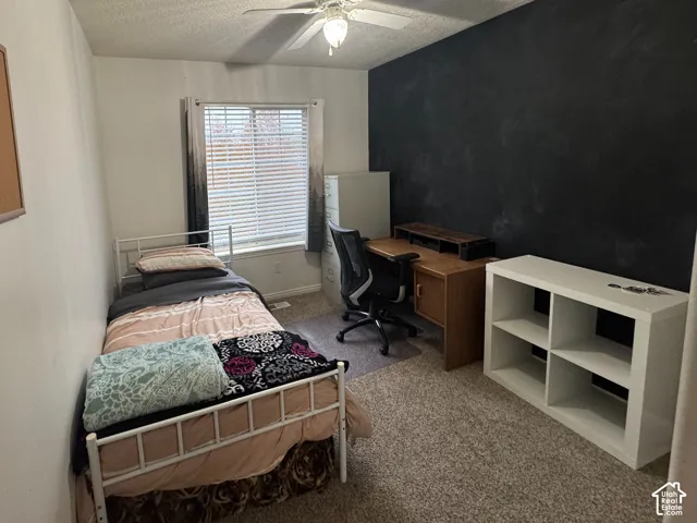 Bedroom 3  featuring a ceiling fan, textured ceiling, window with blinds, and a dark accent wall