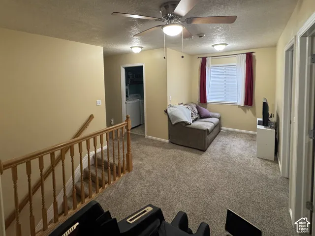 Carpeted Loft Family Room with a ceiling fan, window with blinds, and wood handrail