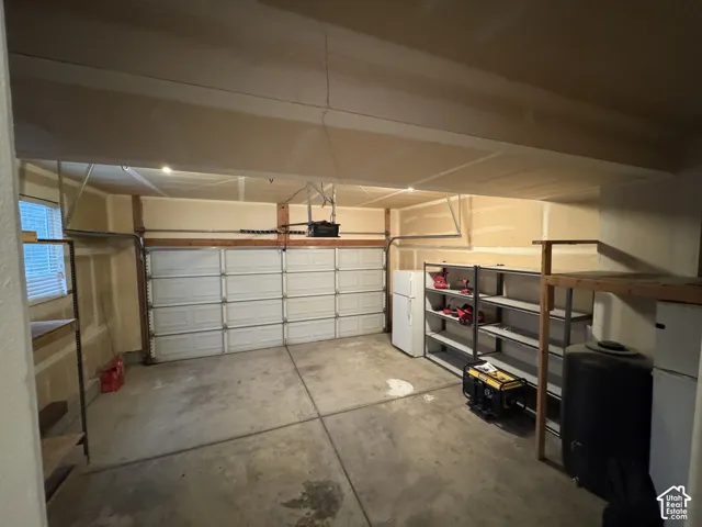 Two-car garage featuring a window, built-in shelving, and overhead lighting