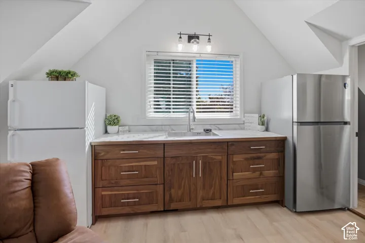 Wood-finish cabinetry with silver-tone hardware, integrated sink, and white countertop