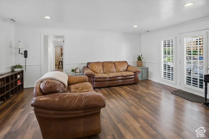 Wood-finish flooring throughout, recessed lighting, white paneling, and white French doors with louvered shutters
