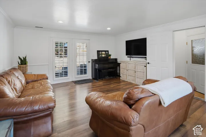 Wood-finish flooring, recessed lighting, crown molding, white paneled doors, and white plantation shutters