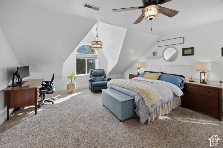 Spacious room featuring vaulted ceilings, a prominent arched window, a ceiling fan with integrated lighting, and plush carpeting
