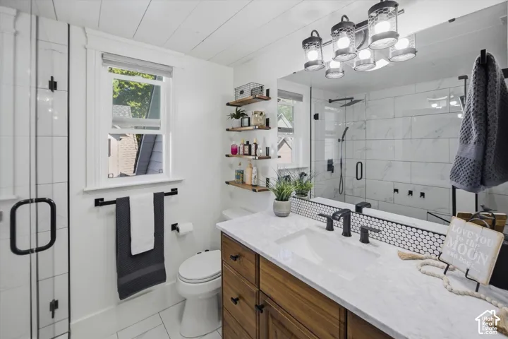 Vanity with wood-finish cabinetry and white countertop, black fixtures, and a hexagon tile backsplash