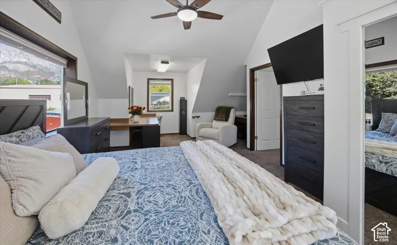 Sloped ceilings with a ceiling fan, a large window with mountain scenery, and a built-in desk area