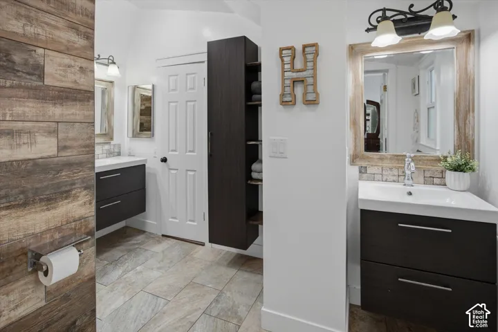 Dual floating vanities with integrated sinks, wood-finish tile flooring, and dark wood-finish built-in storage