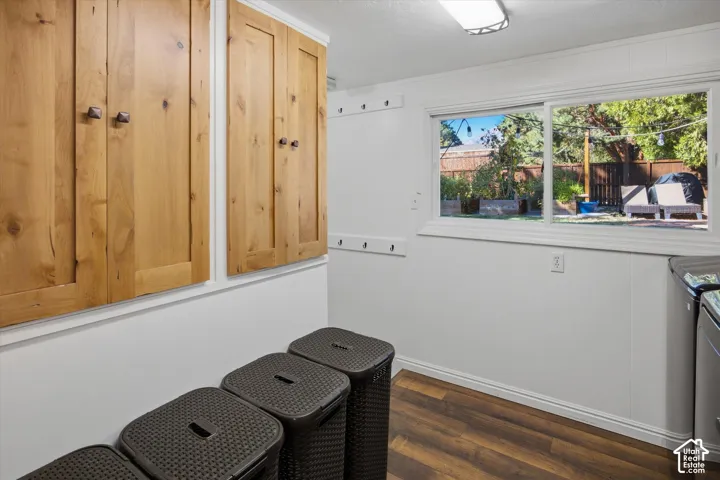 Wood-finish flooring, overhead cabinetry with bronze hardware, sliding window, and integrated wall hooks