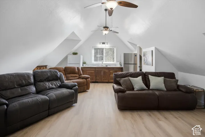 Vaulted ceilings featuring two ceiling fans, wood-finish flooring, and built-in cabinetry with a white countertop