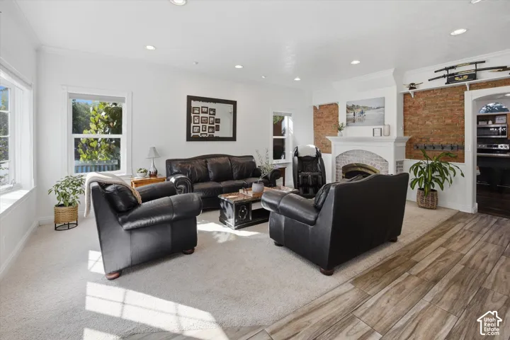 Recessed lighting illuminating a spacious living area with a fireplace featuring a white mantel and brick surround