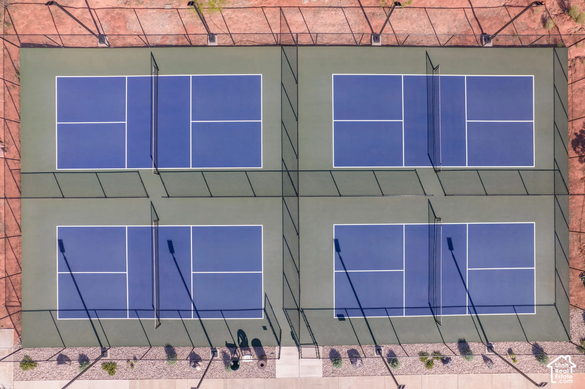 Four fenced pickleball courts with blue and green surfaces