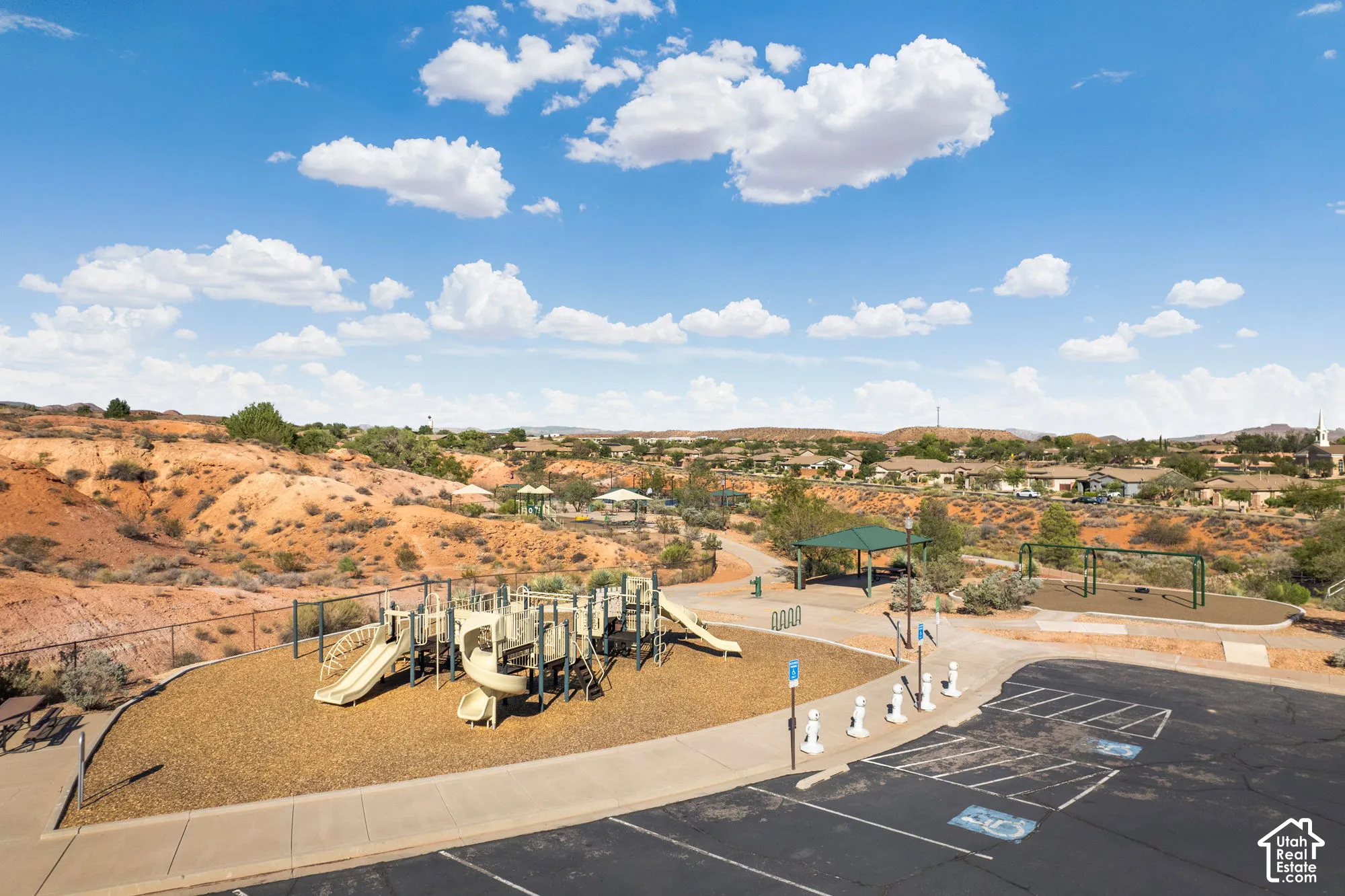 Community park featuring a large play structure, swing sets, covered picnic areas, and paved walking paths
