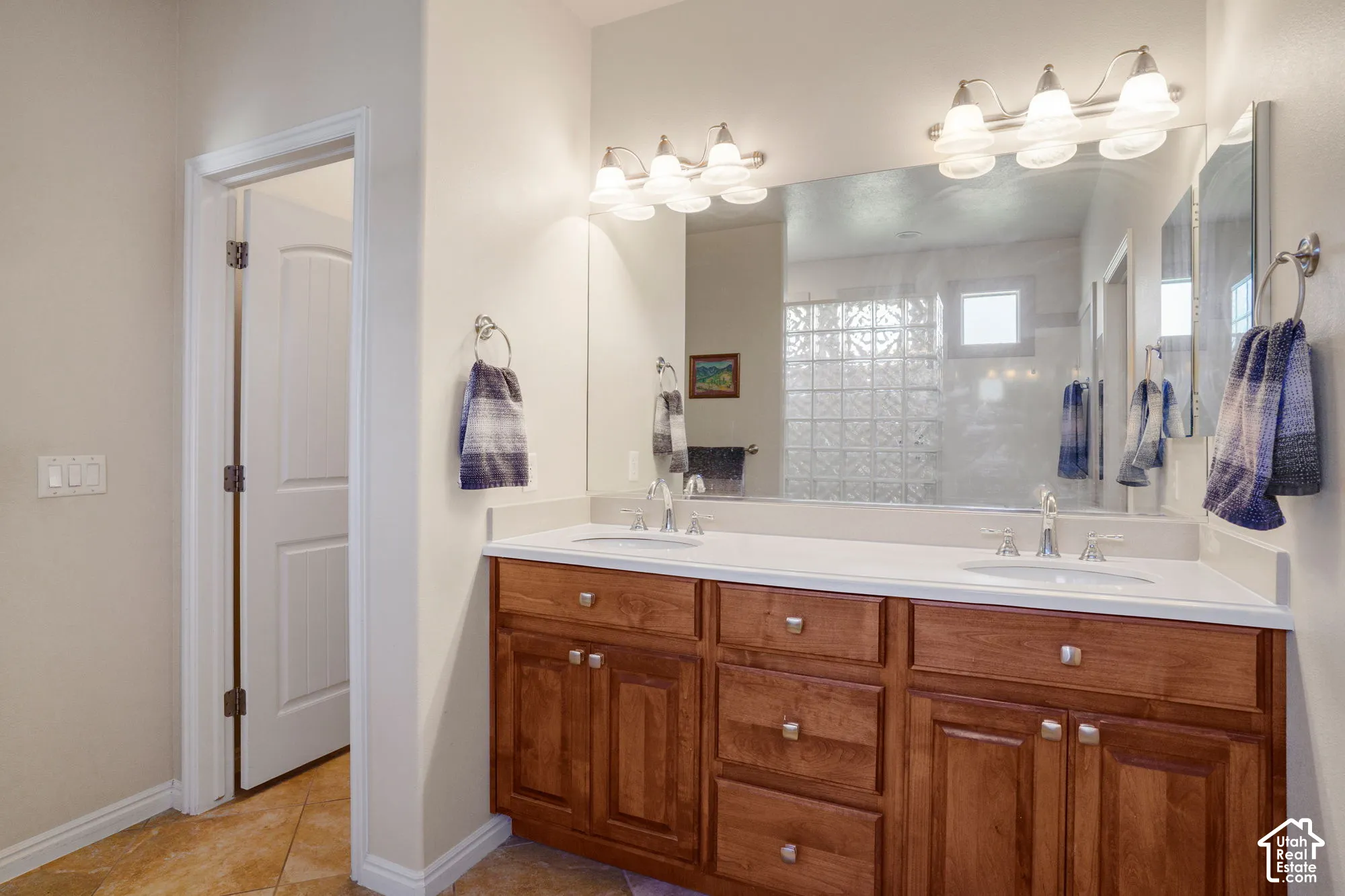 Double vanity with wood cabinetry, dual undermount sinks, and a large wall-mounted mirror