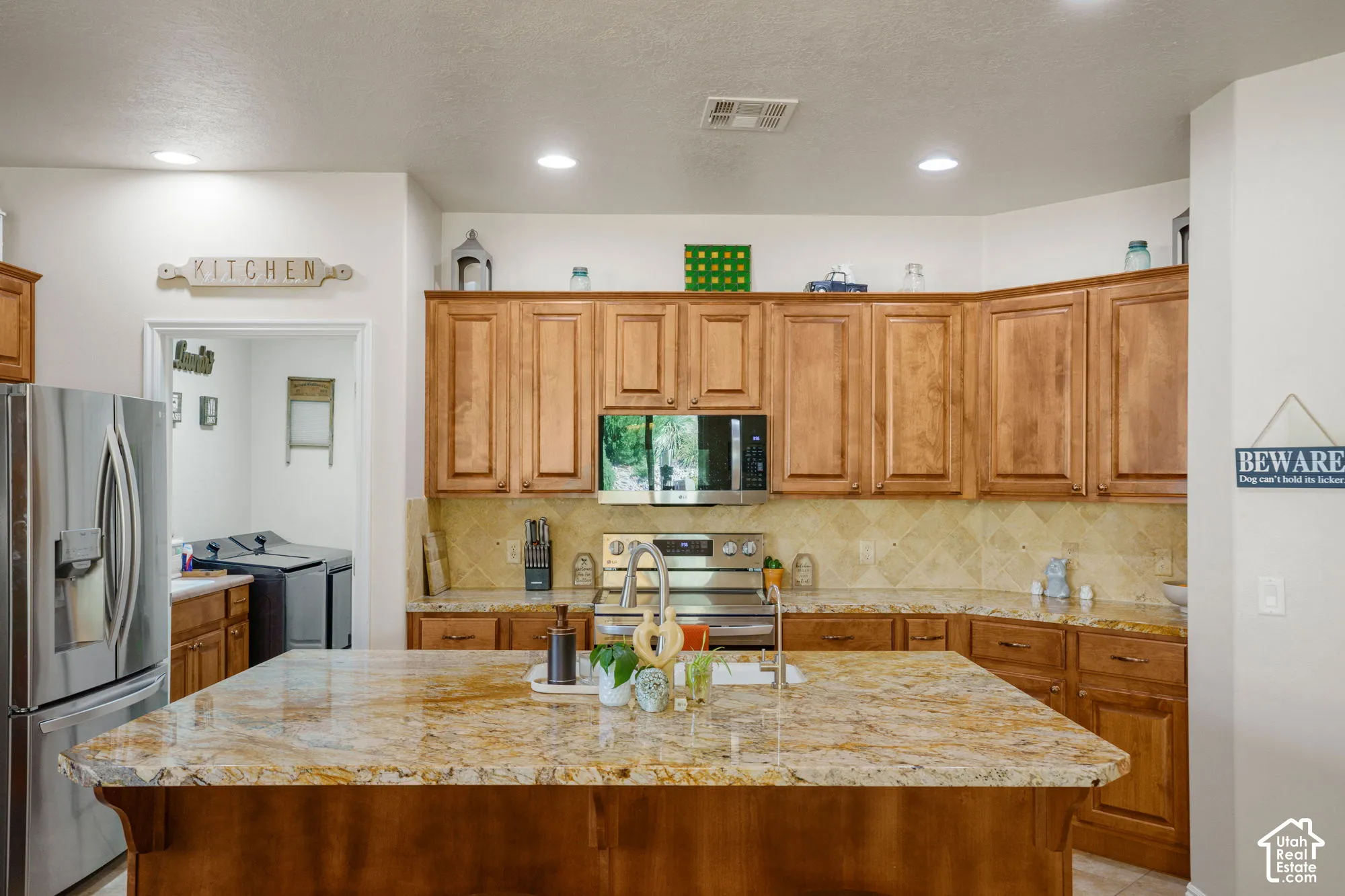 Kitchen featuring a large center island with a stone countertop, wood cabinetry, stainless steel appliances, and recessed lighting