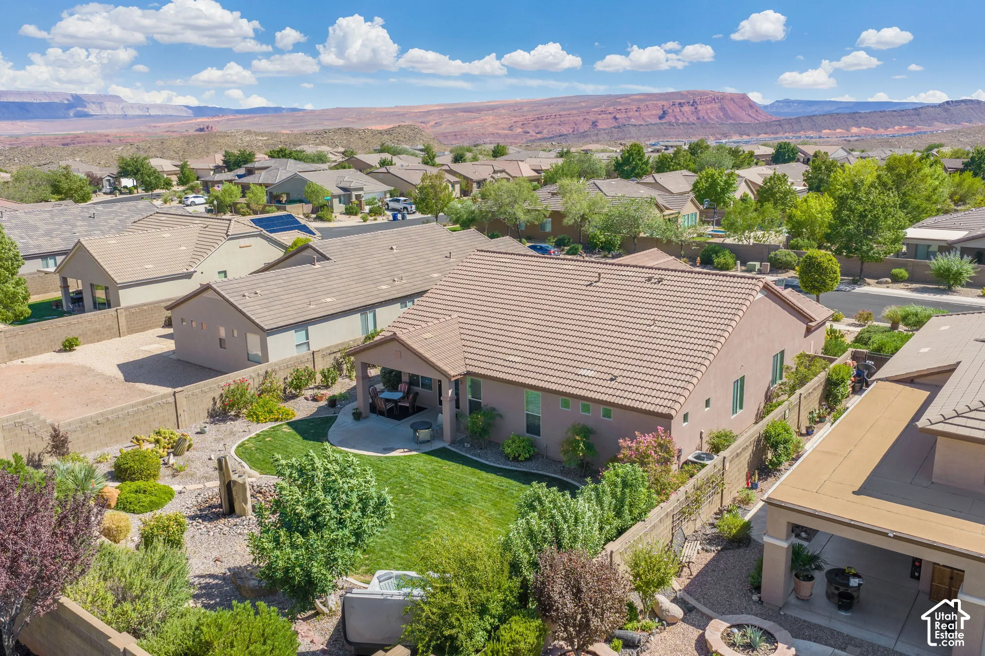 Expansive backyard with a manicured lawn, established landscaping, and a covered patio