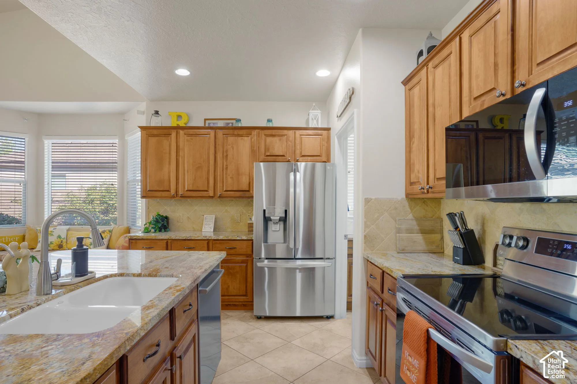 Kitchen featuring wood cabinetry, stainless steel appliances, a large basin sink, and granite countertops