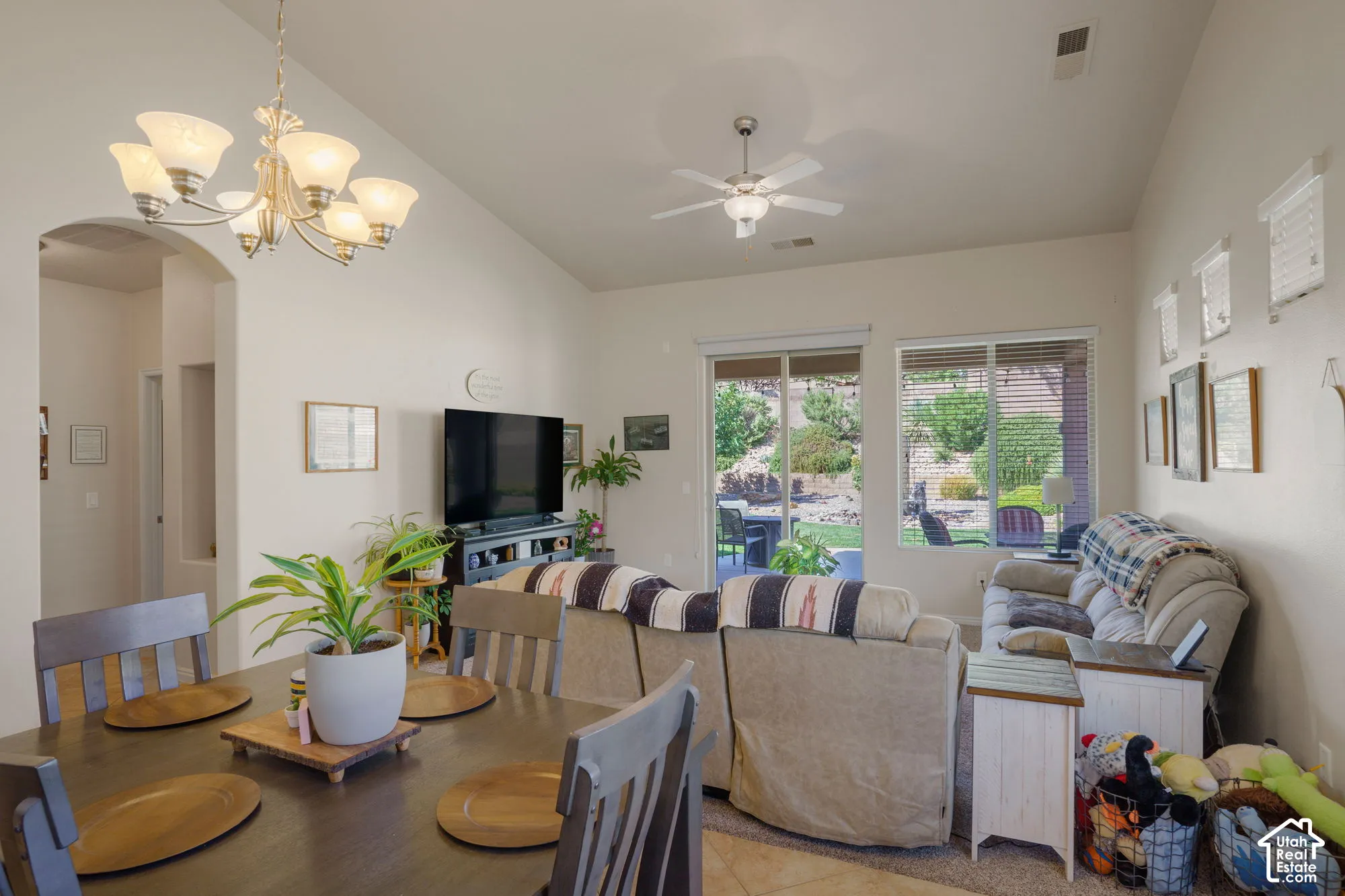 Vaulted ceilings with a ceiling fan, recessed lighting, and a chandelier illuminate the open living area