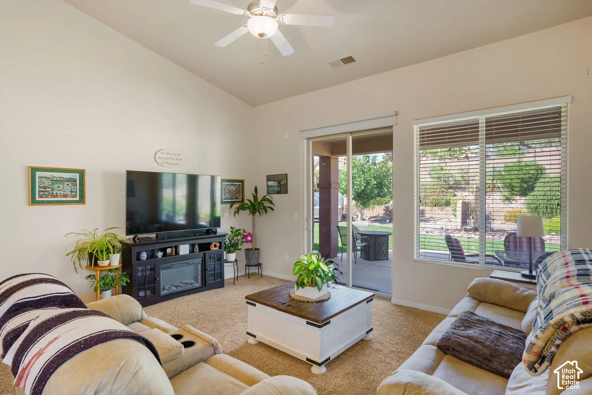 Vaulted ceiling, ceiling fan, carpet flooring, electric fireplace, and sliding glass door