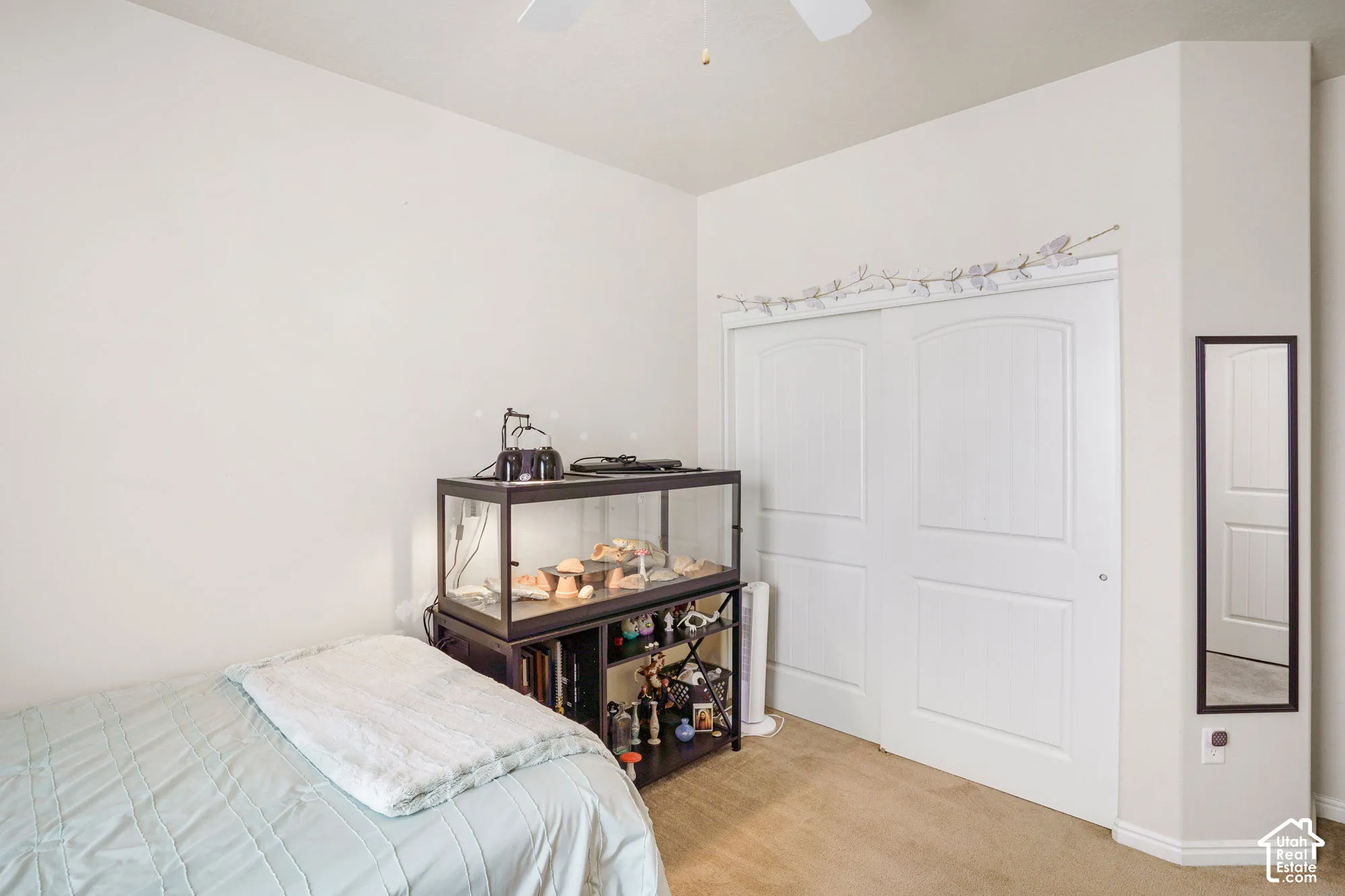 White paneled bi-fold closet doors, light neutral wall paint, and ceiling fan