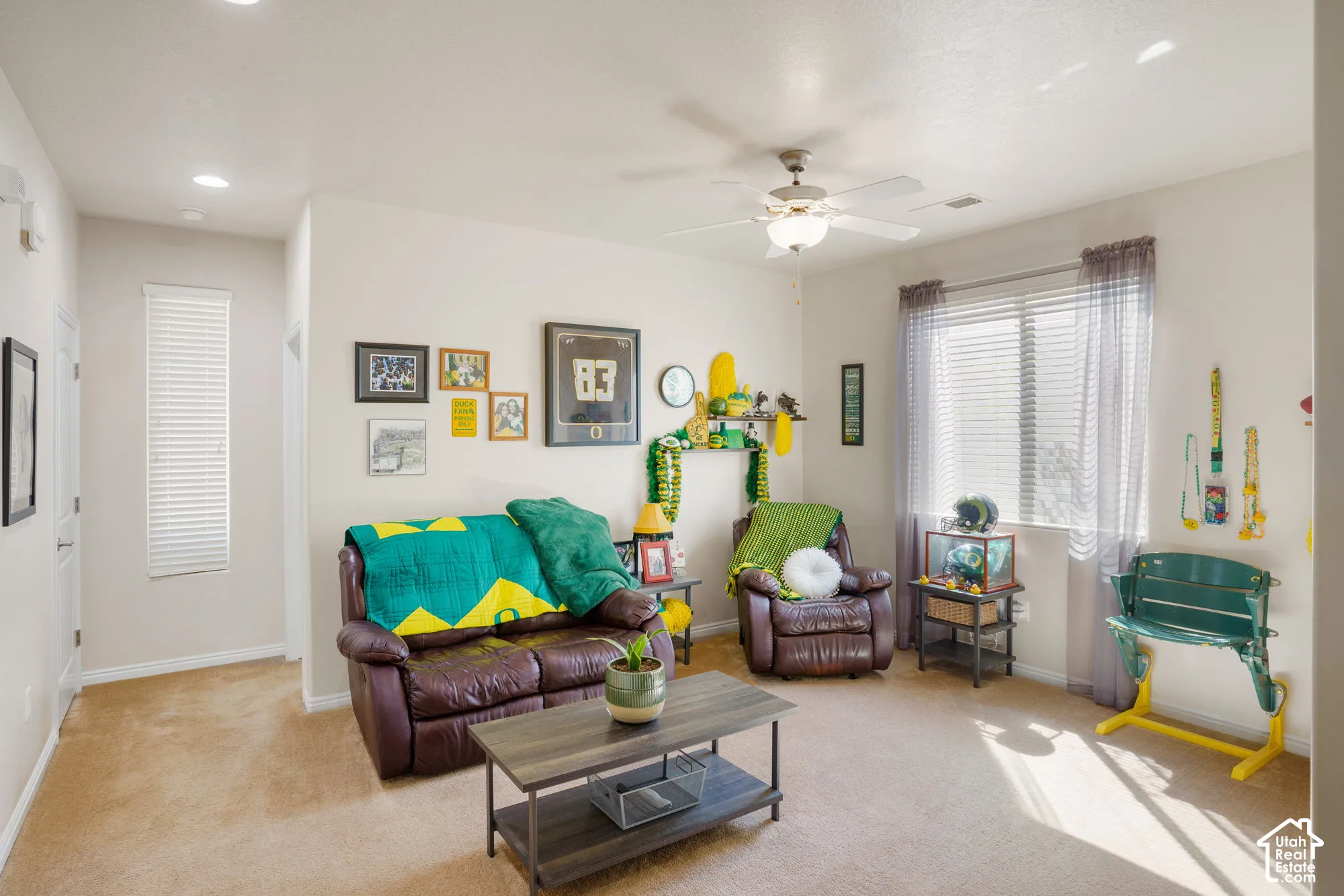 Carpeted living space featuring a ceiling fan, recessed lighting, and a large window with horizontal blinds