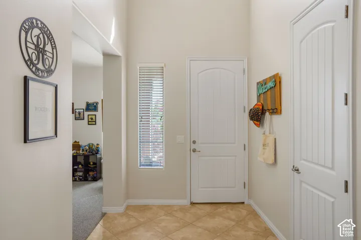 Tiled flooring, high ceilings, vertical window blinds, and white interior doors with arched top panels
