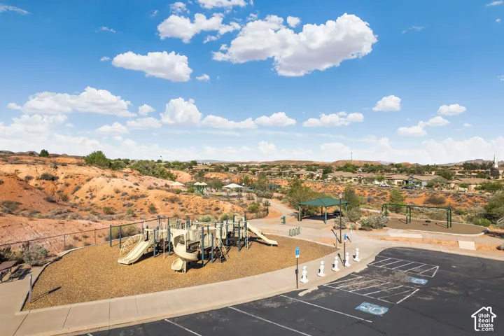 Community park featuring a large play structure, swing sets, covered picnic areas, and paved walking paths