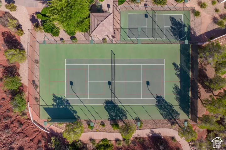Two full-sized tennis courts with chain-link fencing, surrounded by paved pathways and desert landscaping