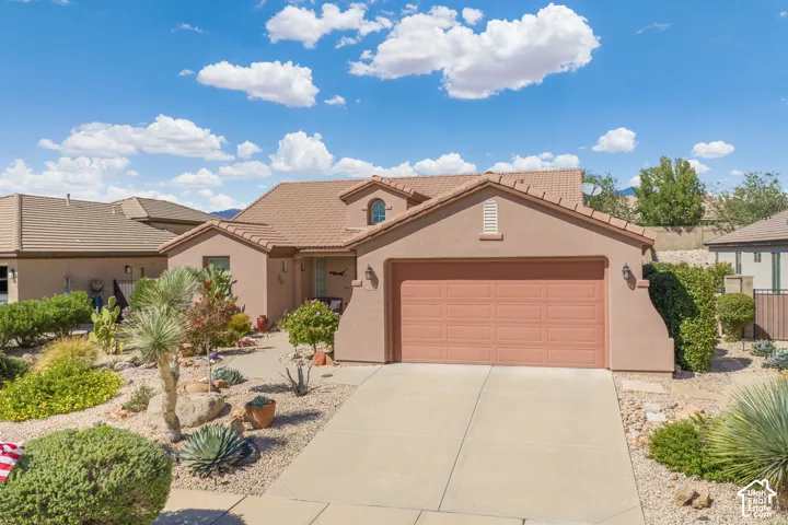 Stucco exterior with a terracotta tile roof, attached garage, and a concrete driveway