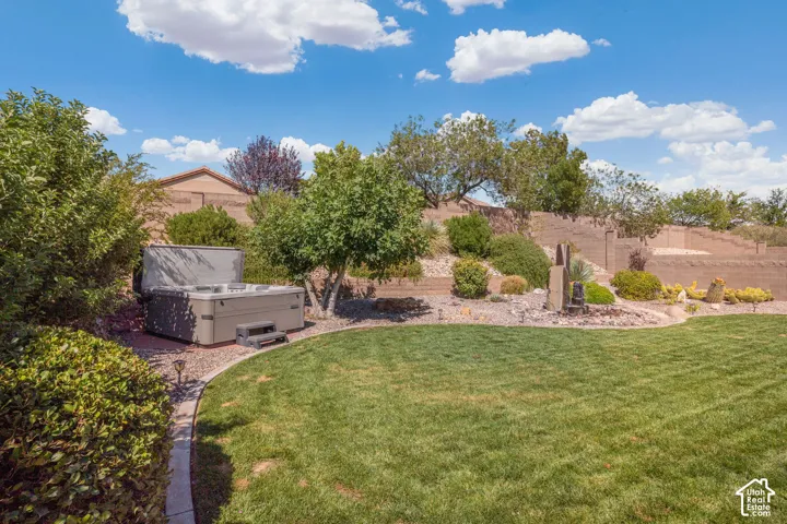 Expansive manicured lawn with a curved paver pathway, featuring a built-in spa, a multi-tiered retaining wall, and mature landscaping with a water feature