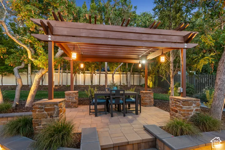 Outdoor pergola with integrated lighting, stone-clad bases, and a paver patio