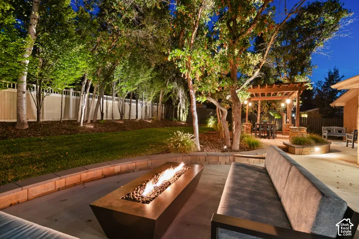 Outdoor patio with built-in fire pit, stone retaining walls, and a wood pergola