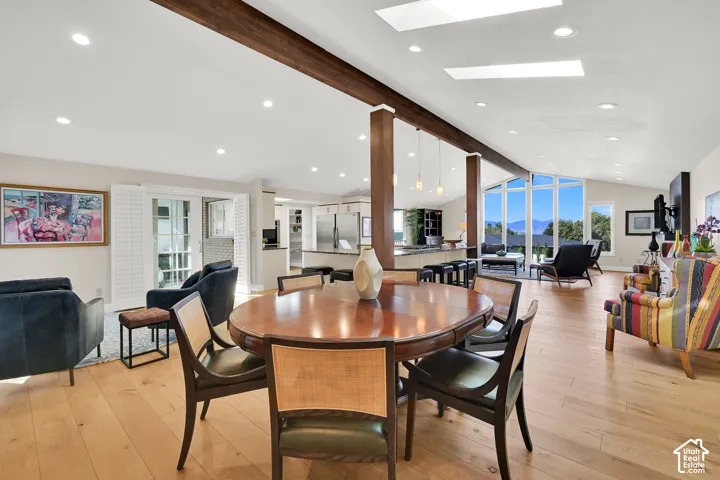 Open-concept living space featuring wood-finish flooring, exposed ceiling beams, recessed lighting, and expansive windows